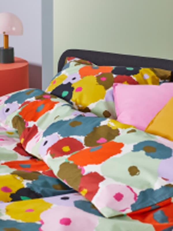 A SLATTUM bed dressed with floral MURREVA duvet cover and floran MURREVA pillowcases.