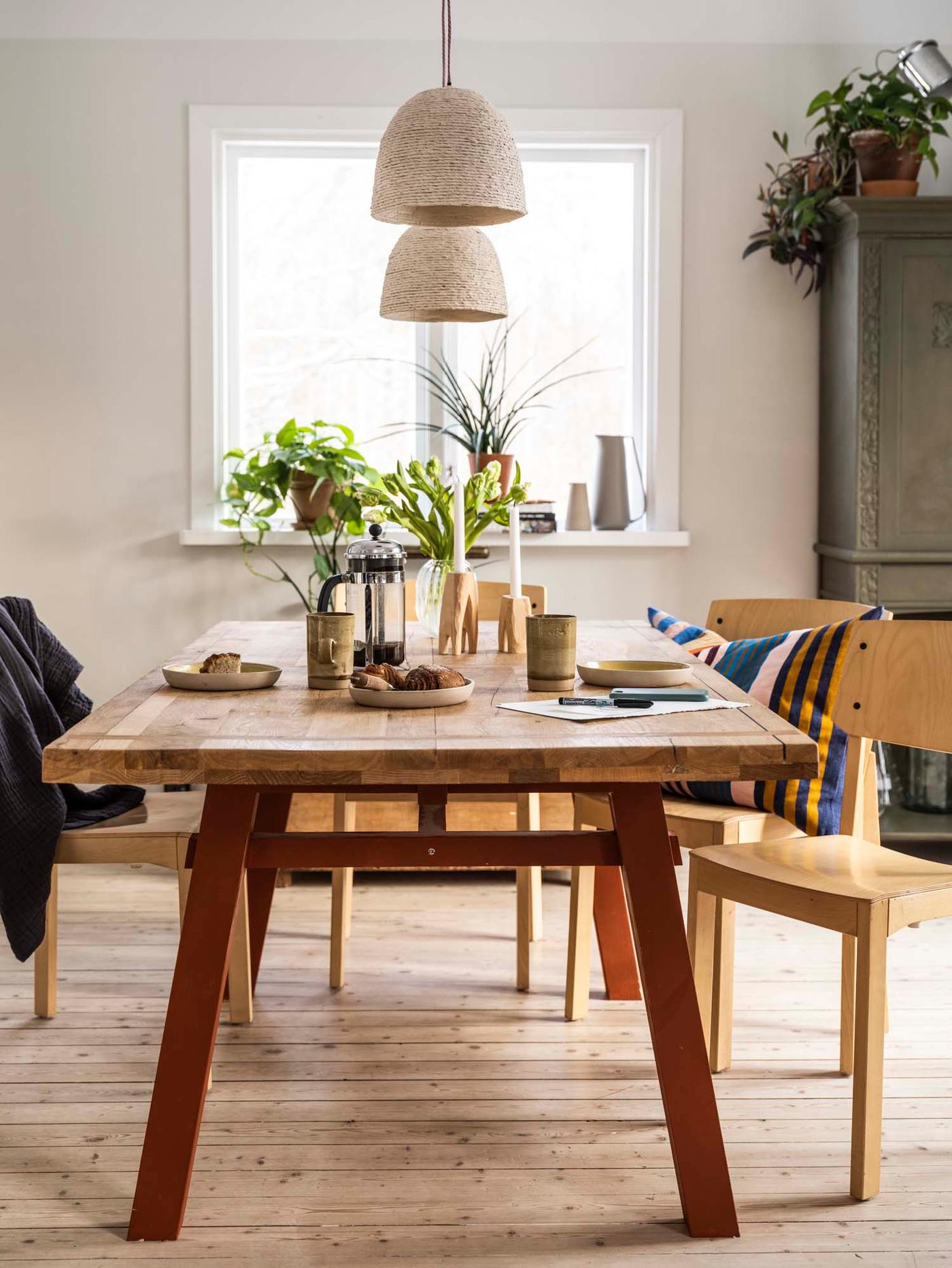 A rustic dining table with candles, coffee and cinnamon rolls. 