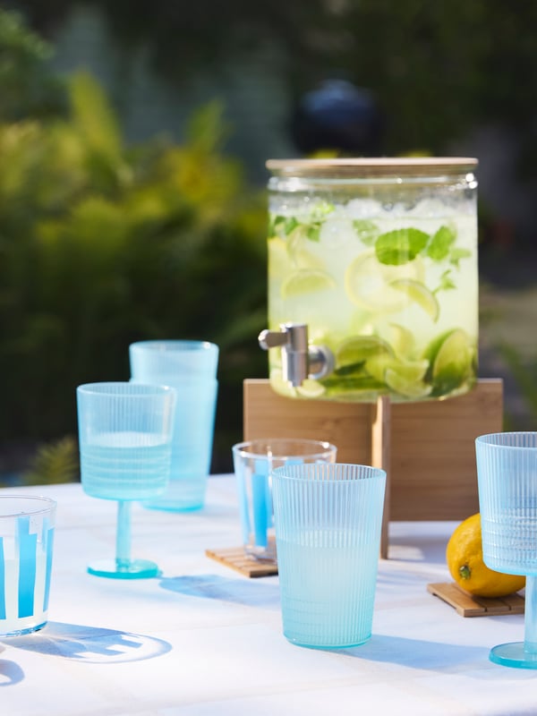 KALLSINNIG and PILLESTARR blue glasses on an outdoor table, along with an IKEA 365+ jar filled with lemonade.