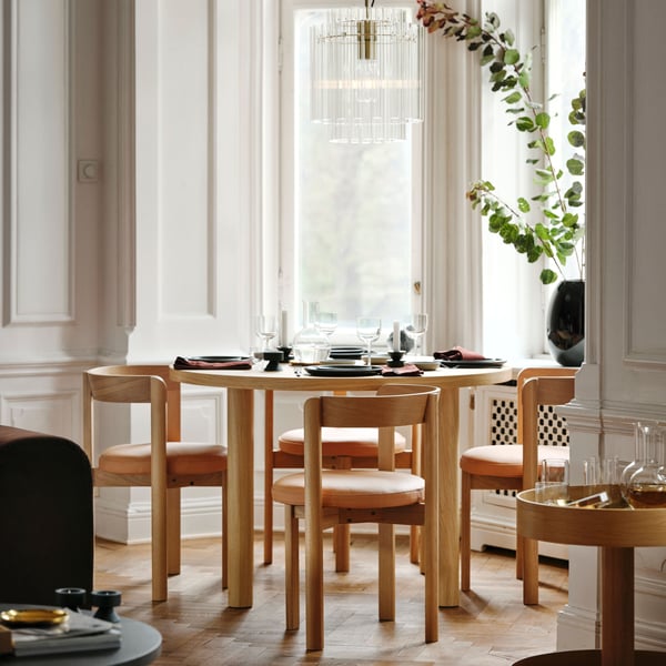 Four STOCKHOLM 2025 oak chairs with leather seats around an oak veneer table by a living room window.